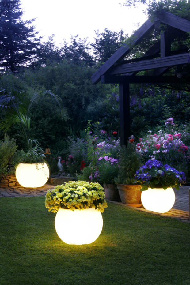 Садовый участок украшенный при помощи кашпо с необыкновенной подсветкой.
