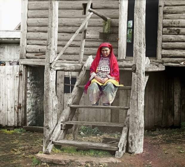Башкирская женщина сидит на деревянной лестнице.