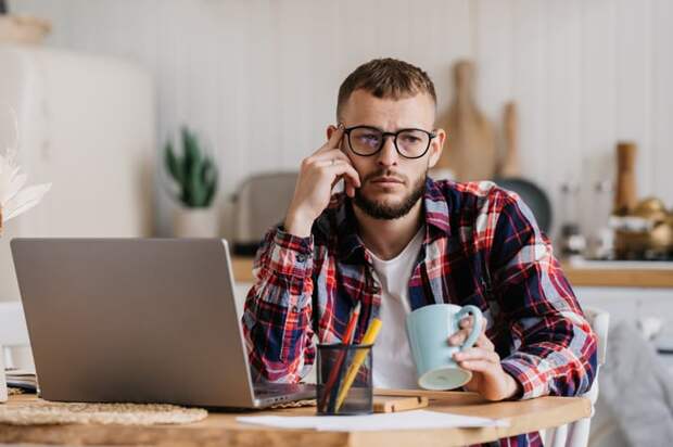A person at a laptop holding a mug.