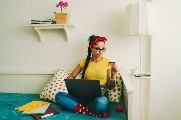 Woman relaxing at home looking at a credit card in her hand.