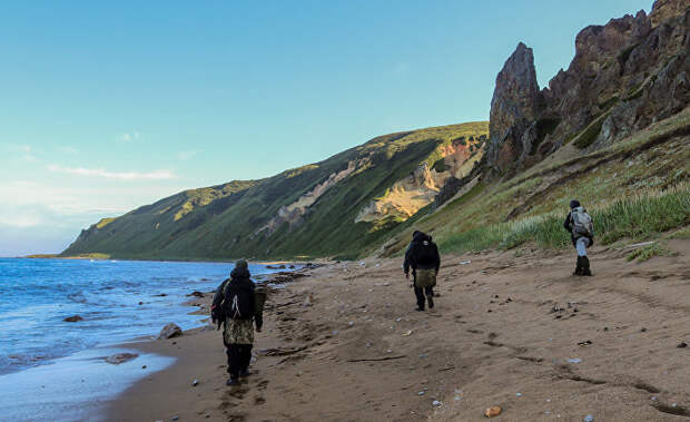 Участники экспедиции идут по берегу бухты Тетяева острова Уруп (остров южной группы Большой гряды Курильских островов).