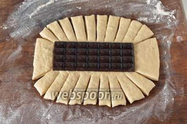 Раскатать тесто в овальный пласт толщиной 0,6-0,7 сантиметра. На середину выложить плитку шоколада. Сделать на тесте насечки-полоски.