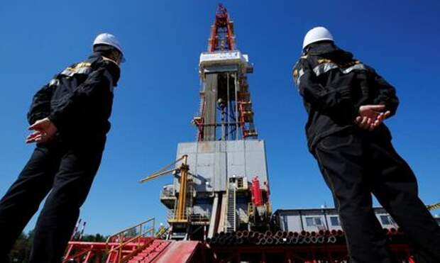 Workers look at a drilling rig at a well pad of the Rosneft-owned Prirazlomnoye oil field outside the West Siberian city of Nefteyugansk, Russia, August 4, 2016. REUTERS/Sergei Karpukhin/File Photo TPX IMAGES OF THE DAY