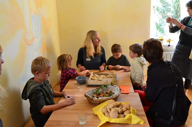 Дети пекут хлеб к завтраку в вальдорфском детсаду. Не страшно, если кто-то кашляет или сморкается: воспитательница может и лекарство дать, и в нос закапать.
