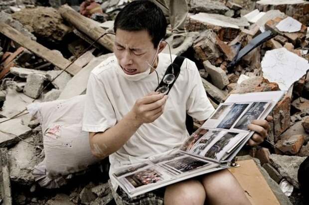 Парень смотрит семейный альбом, который нашел в щебне своего старого дома после землетрясения в Сычуани. история, события, фото
