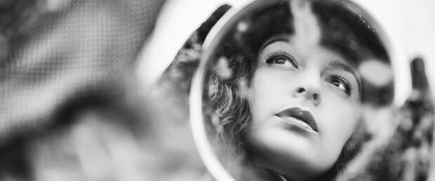 Face reflection on mirror of beautiful pensive woman