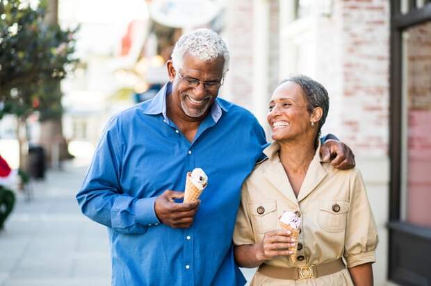 Two smiling people walking down street with ice cream cones.