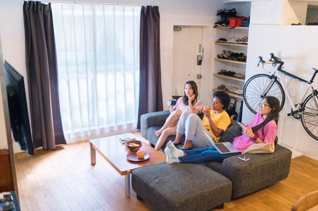 Three roommates sitting on the couch in their apartment.