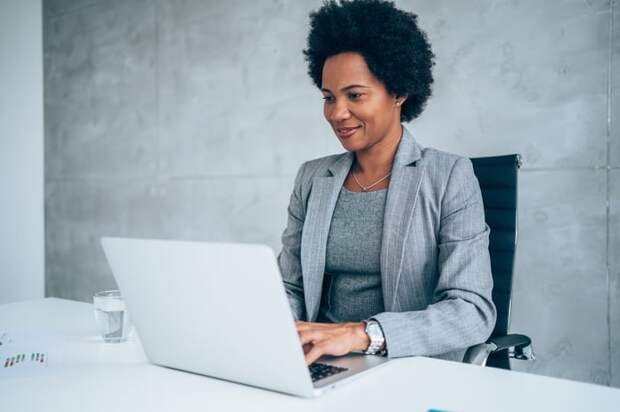 A smiling person at a laptop.