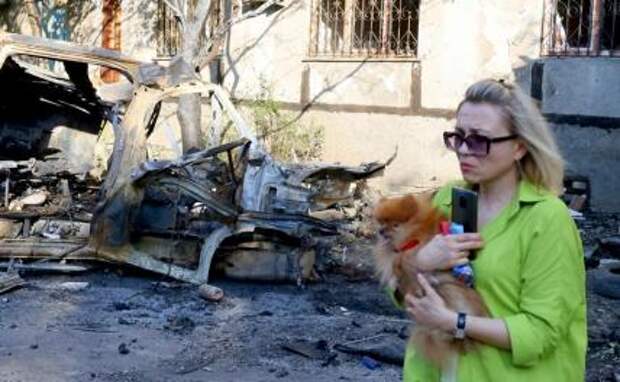 На фото: женщина у сгоревшей машины скорой помощи после обстрелов в Куйбышевском районе Донецка