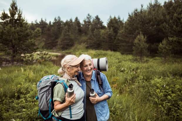 Two adults in field with water bottles and backpacks.