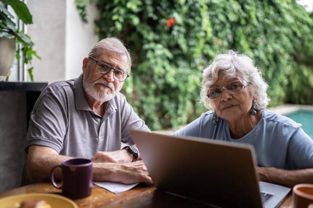 Two people at a laptop with serious expressions.