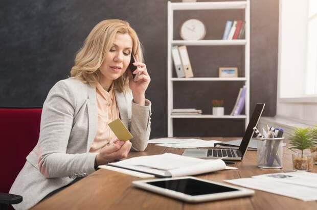 Woman holding credit card while talking on phone