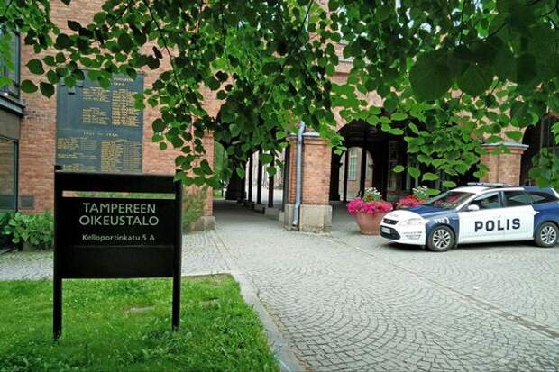 Pirkanmaan käräjäoikeuden rakennus ulkoa kuvattuna. Talon edessä poliisiauto.