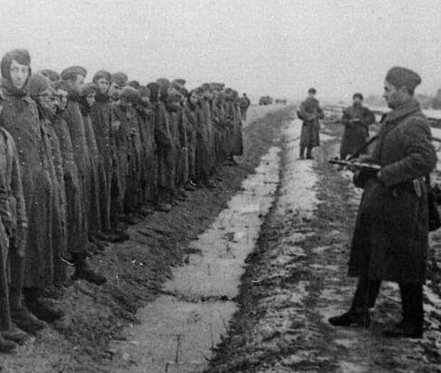 Пленные немцы и охраняющие их советские солдаты с автоматами.
