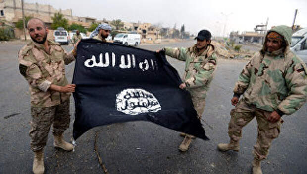 Бойцы сирийского отряда народного ополчения Соколы пустыни демонстрируют флаг Исламского государства (ИГ, запрещена в РФ)