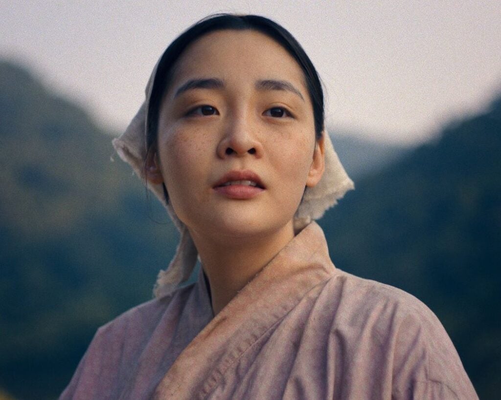 Vertical Headshot of Sunja with hair tied back in a beige scarf