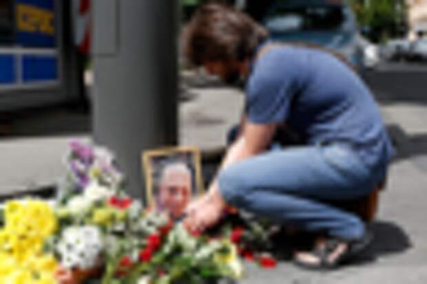 A man lights a candle by a portrait of Pavel Sheremet surrounded with flowers and candles at a place of his death in Kiev, Ukraine, Wednesday, July 20, 2016. A prominent journalist was killed in a car bombing in Ukraine's capital, Kiev, on Wednesday, sending shockwaves through the Ukrainian journalist community that was shaped by the gruesome killing of the publication's founder 16 years ago. (AP Photo/Sergei Chusavkov)