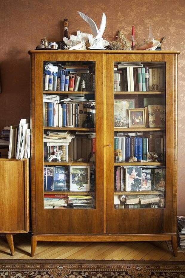 Старый шкаф с книгами и статуэтками.
