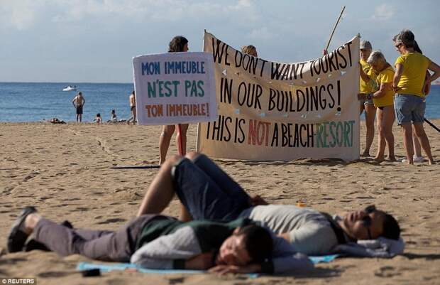 Демонстрация проводилась неподалеку от гуляк, отсыпающихся на пляже после ночного кутежа барселона, испания, каталония, местные жители, пляж, протест, протестующие, туризм