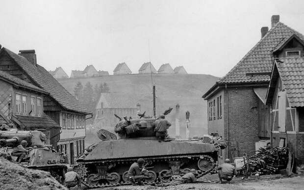 Солдаты 1-й пехотной дивизии укрываются от огня не обнаруженного немецкого снайпера за танками M4A3 «Шерман» 745-го танкового батальона армии США в Санкт-Андреасберге, Германия Великая отечественая война, архивные фотографии, вторая мировая война