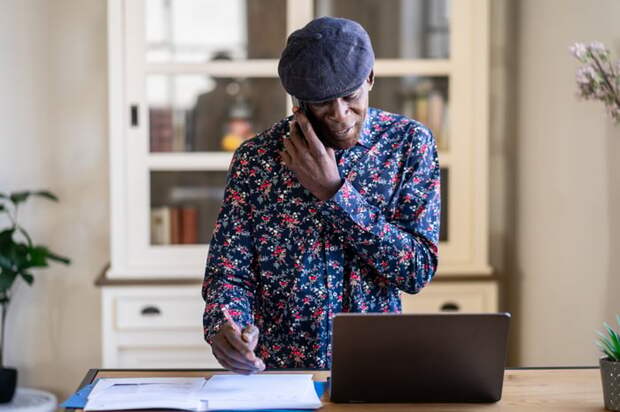 Someone holding a phone to their ear while holding a pen in the other hand.