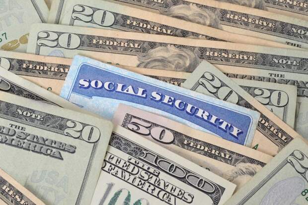 A blue Social Security card among a pile of various U.S. currency
