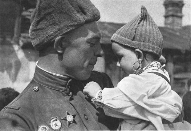 Советский солдат с чешским ребенком на руках. Малыш рассматривает орден Славы на груди бойца.Прага, Чехословакия. Май 1945 Советский солдат с чешским ребенком на руках. Малыш рассматривает орден Славы на груди бойца.Прага, Чехословакия. Май 1945