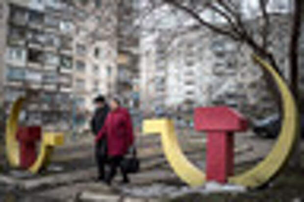 Local residents walk past Soviet-era hammer and sickle sculptures outside an apartment building damaged after Saturday's shellingin Mariupol, Ukraine, Wednesday, Jan. 28, 2015. The military conflict between Russia-backed separatists and the government forces in eastern Ukraine has been raging since April, claiming more than 5,100 lives, according to the United Nations. (AP Photo/Evgeniy Maloletka)