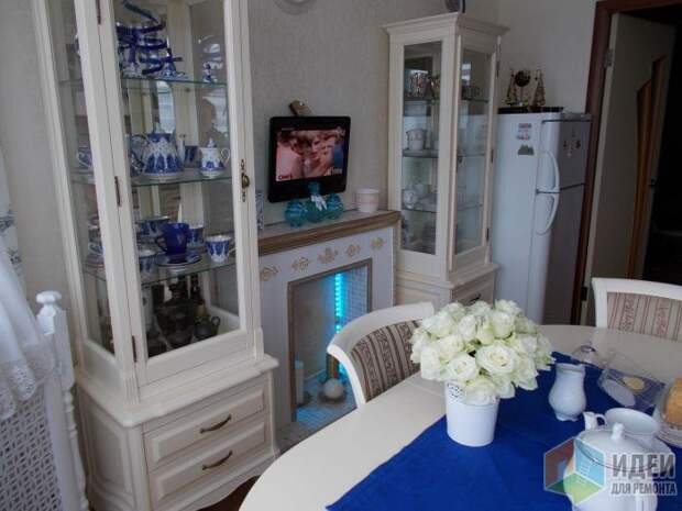Бело-синяя кухня, витрины для посуды, камин с подсветкой
