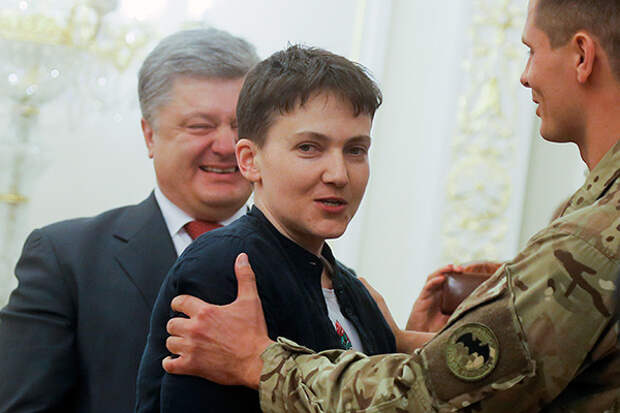 Ukrainian President Petro Poroshenko,  left, smiles, as Ukrainian jailed pilot Nadezhda Savchenko, center is congratulated by servicemen of the Aidar battalion, in the Presidential Office in Kiev, Ukraine, Wednesday, May 25, 2016. Russia has released jailed pilot Nadezhda Savchenko, as part of a swap for two Russian servicemen imprisoned in Ukraine. (AP Photo/Efrem Lukatsky)