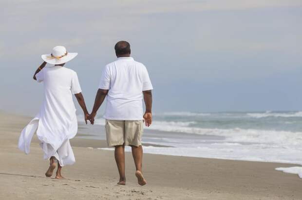 Couple holding hands on the beach.