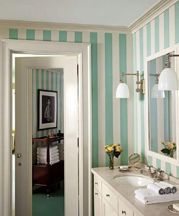 Необычное настроение в ванной комнате создано благодаря полосатым обоям в бело-бирюзовых тонах.