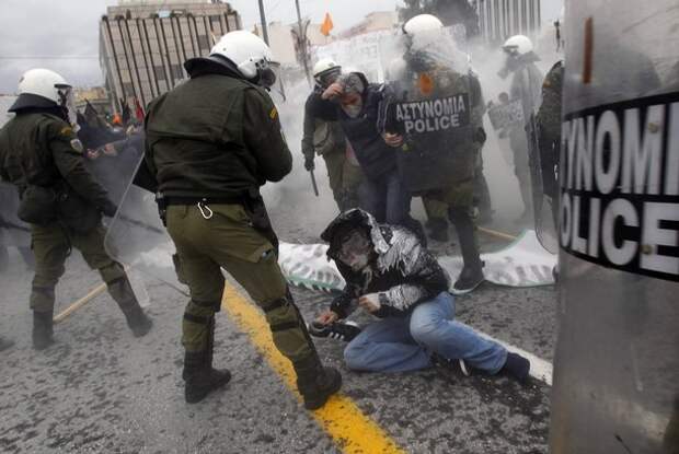 A protester falls on the ground during clashes in central Athens