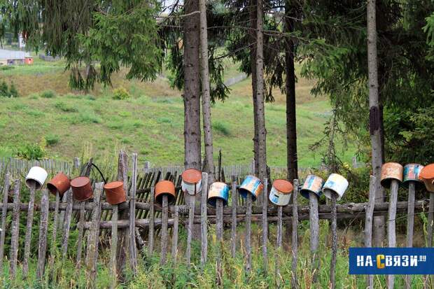 Непринужденно расставленные по кольям ведра придадут забору оригинальный вид.