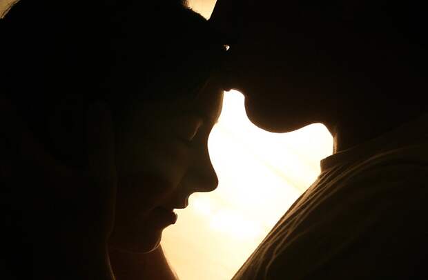 A man kisses a woman's forehead.