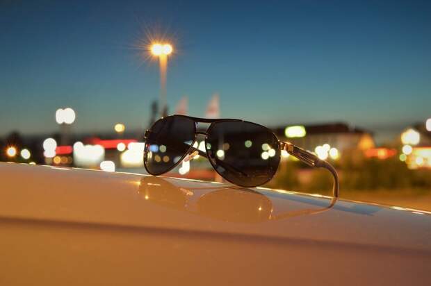 Солнцезащитные очки на фоне вечернего города. /Фото: cdn.pixabay.com