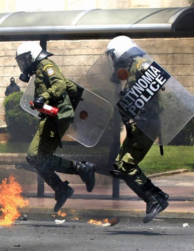 Riot policemen jump to avoid a petrol bomb during clashes with youths in central Athens