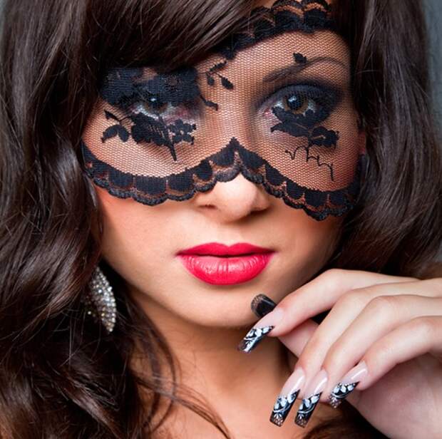 Closeup portrait of attractive young brunette girl with long dark ringlets fine art manicure wearing lacy mask on her eyes