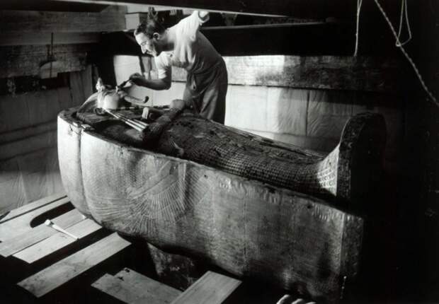 Археолог Говард Картер изучающий саркофаг с мумией фараона Тутанхамона.