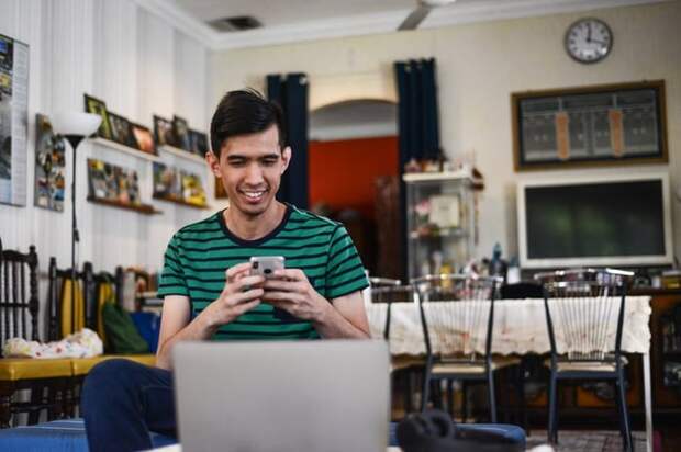 Happy man checks his phone and laptop at home