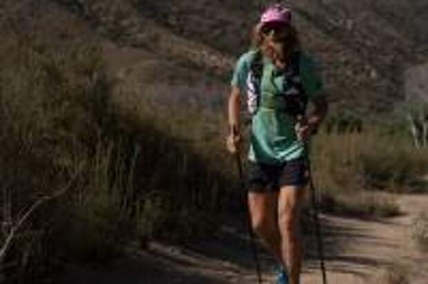 Timothy Olson running with trekking poles and a green shirt and pink hat on the Pacific Crest trail