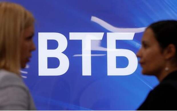 Employees speak near a board with VTB logo during a tour at a branch of VTB bank in Moscow, Russia May 30, 2019. REUTERS/Evgenia Novozhenina