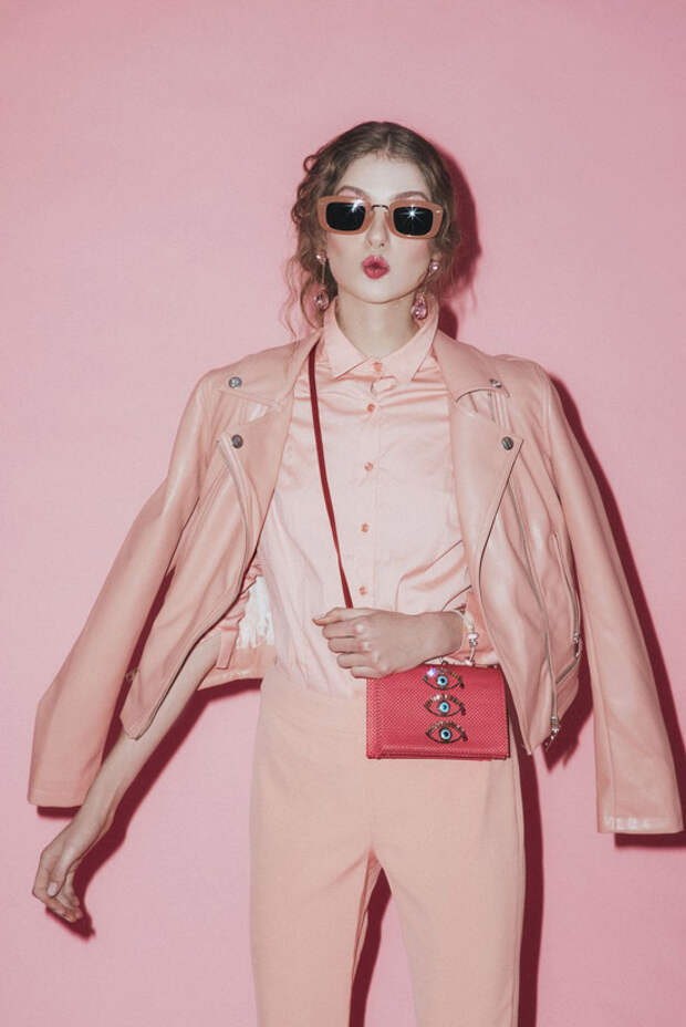 Модель в розовых брюках, рубашка и кожаная куртка, кораловая сумка
