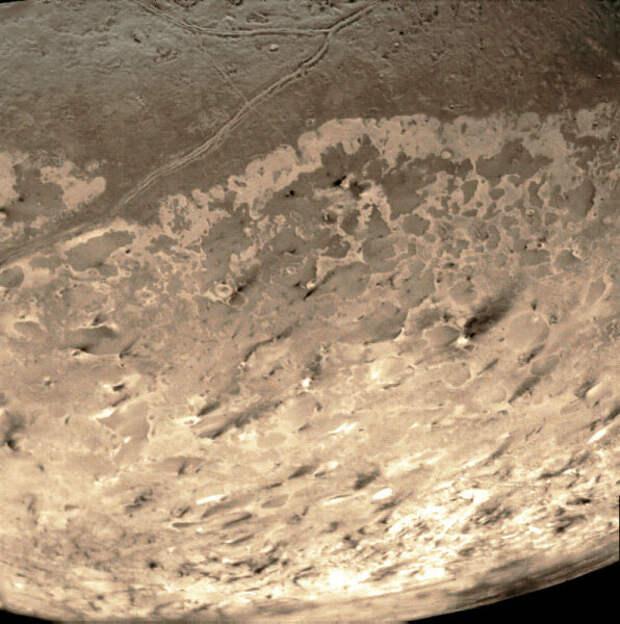 Снимок Тритона, сделанный «Вояджером-2» в 1989 году. Тёмные струи — следы извержений криовулканов