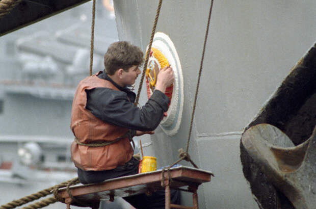 Матрос обновляет красками герб СССР на корме корабля Черноморского флота. 1992 г