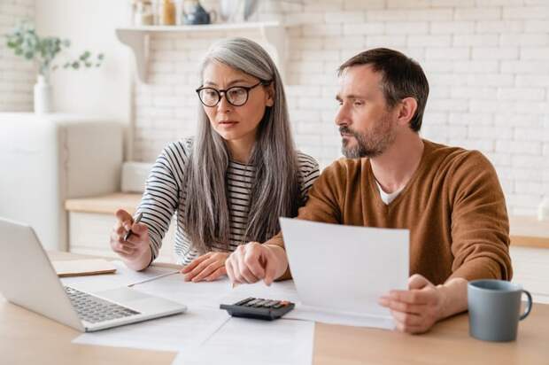 Two people looking at a laptop and documents.