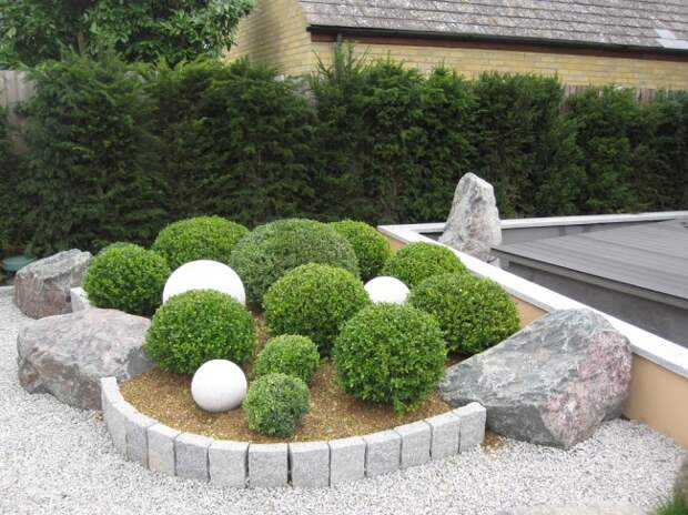 Современная клумба на даче из камней и круглых кустарников