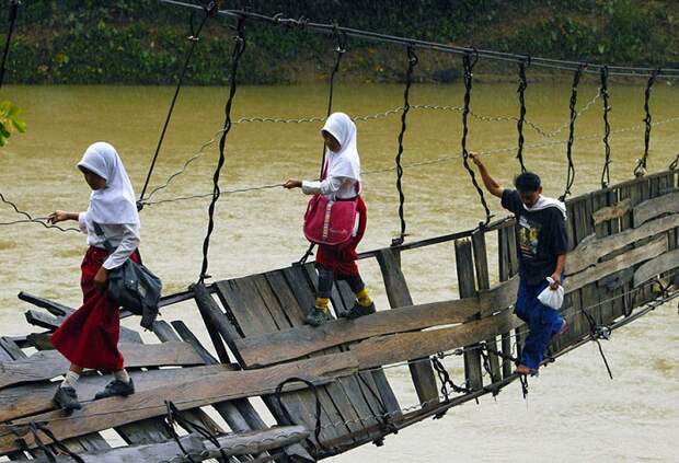Детям приходится переправляться на другой берег по сломанному мосту.