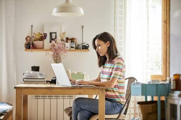 A woman looking something up on her laptop while sitting at a table in her home.
